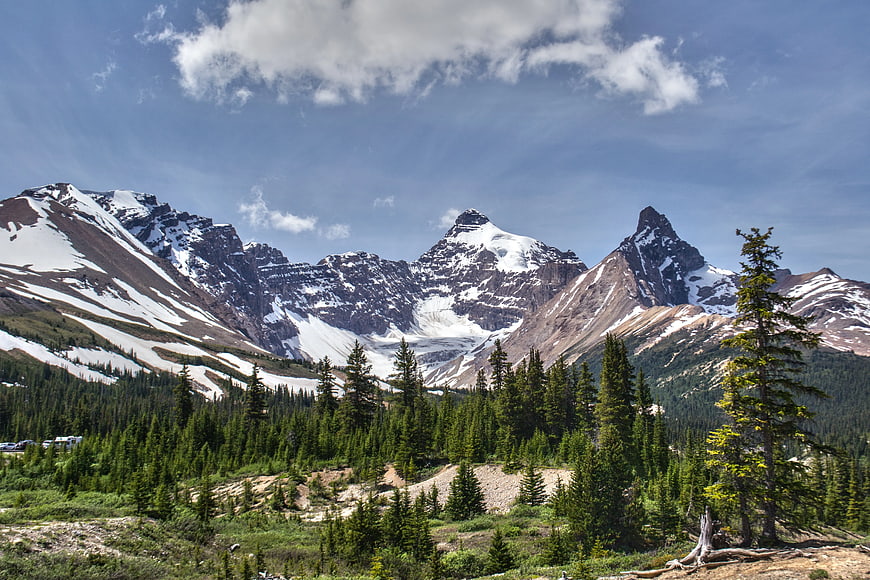 Snowy Mountain Peaks with Pine Forest and Blue Sky