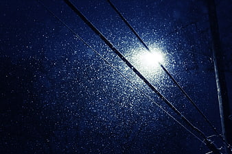 Snowfall illuminated by street light at night with power lines