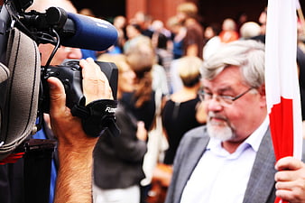 Journalist filming man with flag at public event
