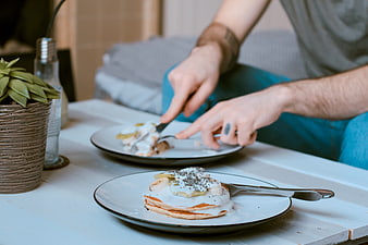 Man Eating Pancakes with Bananas and Yogurt at Wooden Table