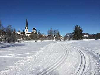 Cross-country ski tracks in snowy winter landscape with church