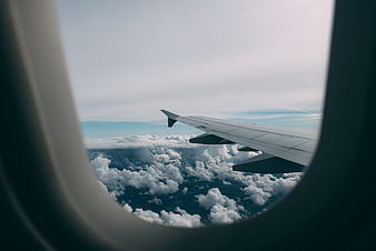 Airplane Wing View Through Window Above Clouds