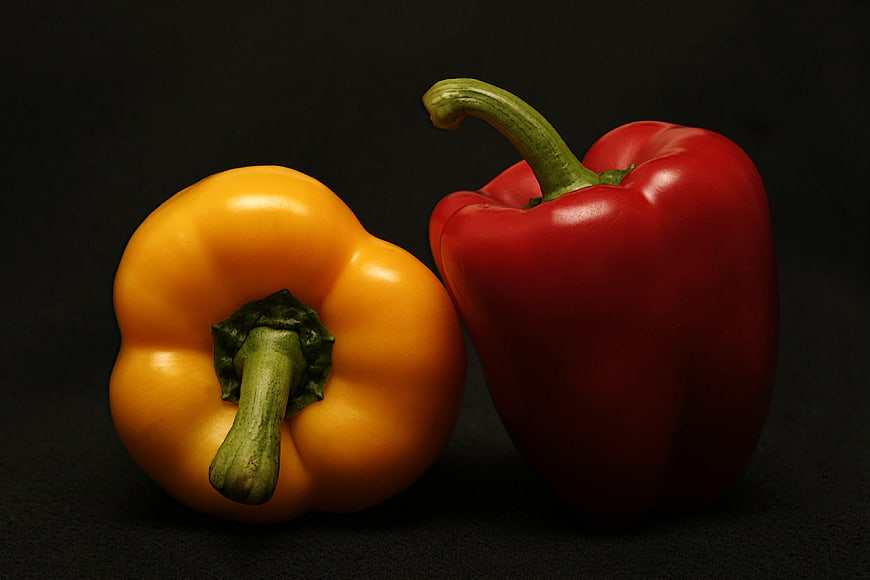 Red and Yellow Bell Peppers on Black Background