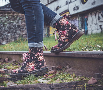 Woman wearing floral boots on train tracks with graffiti background
