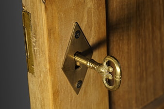 Antique brass key in wooden door lock close-up