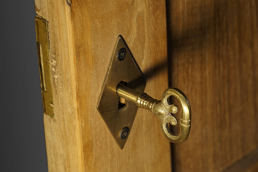 Antique brass key in wooden door lock close-up