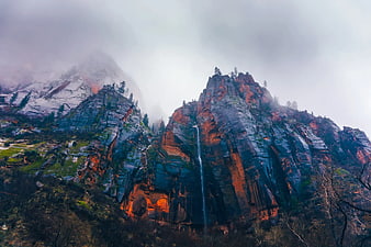 Misty waterfall cascading down rugged red rock mountain cliffs