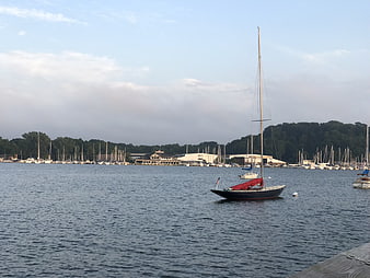 Sailboat with red cover anchored in calm marina bay