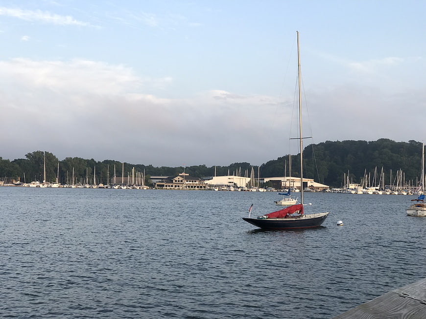 Sailboat with red cover anchored in calm marina bay