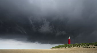 Red Lighthouse on Dunes Under Dark Storm Clouds