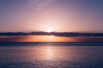 Serene Sunset Over Calm Ocean with Purple and Orange Sky