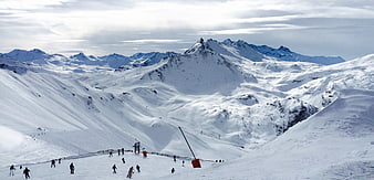 Wide panoramic view of skiers on snowy mountain slopes