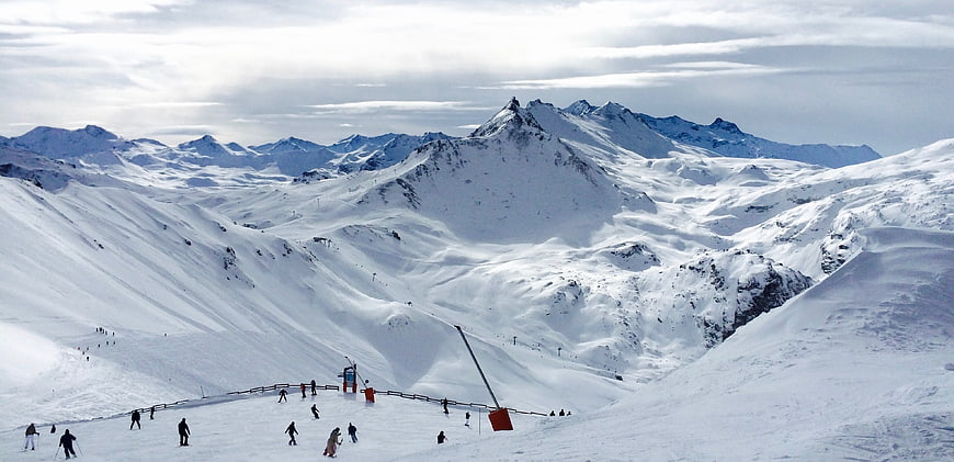 Wide panoramic view of skiers on snowy mountain slopes
