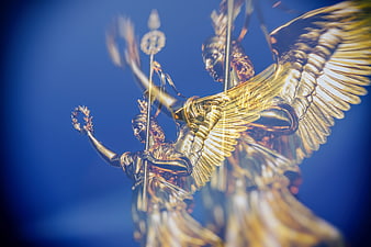 Golden Winged Victory Statues Against Blue Sky
