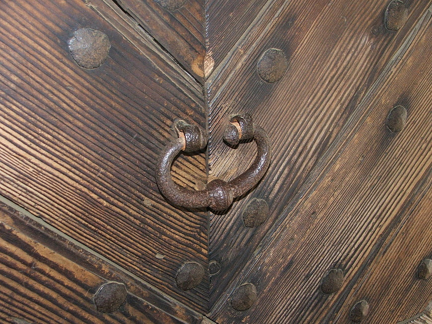 Close-up of antique wooden door with iron handle and rivets