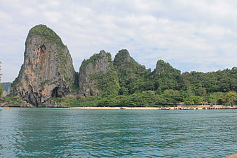 Tropical limestone karst cliffs and beach with longtail boats