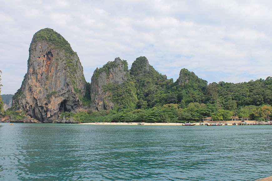 Tropical limestone karst cliffs and beach with longtail boats