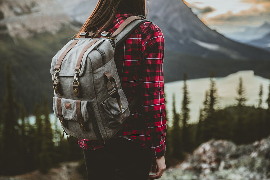 Woman with Backpack Looking at Mountain Lake View