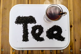 Top view of tea leaves spelling Tea on white tray