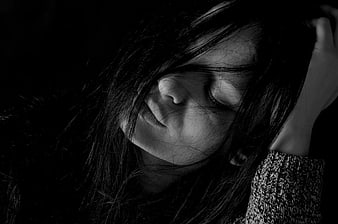 Black and white portrait of a sad woman with hair covering face