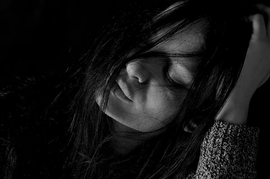 Black and white portrait of a sad woman with hair covering face