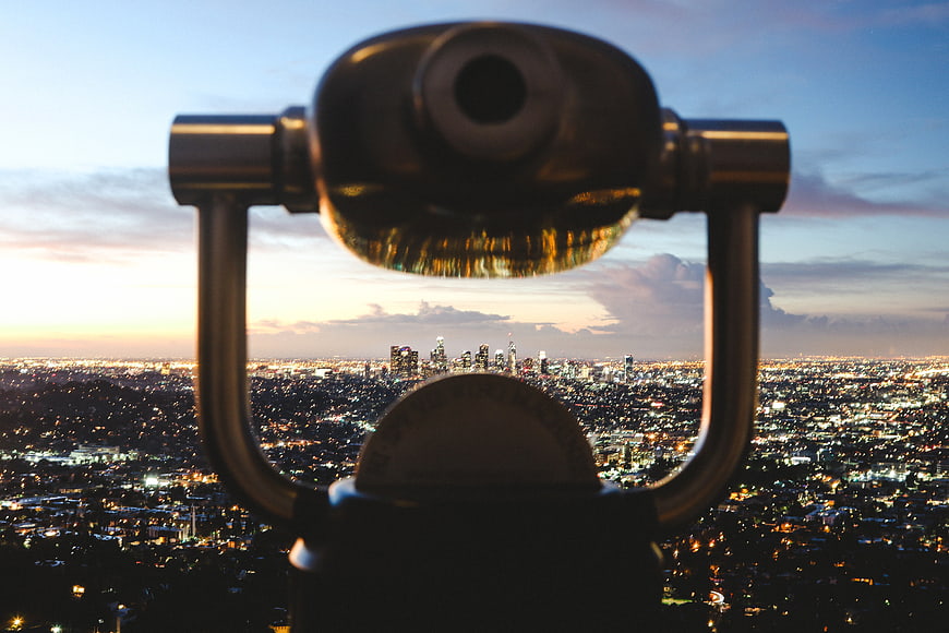 Coin-operated binoculars overlooking city skyline at dusk