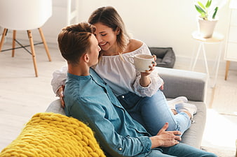 Happy couple relaxing on sofa with coffee at home
