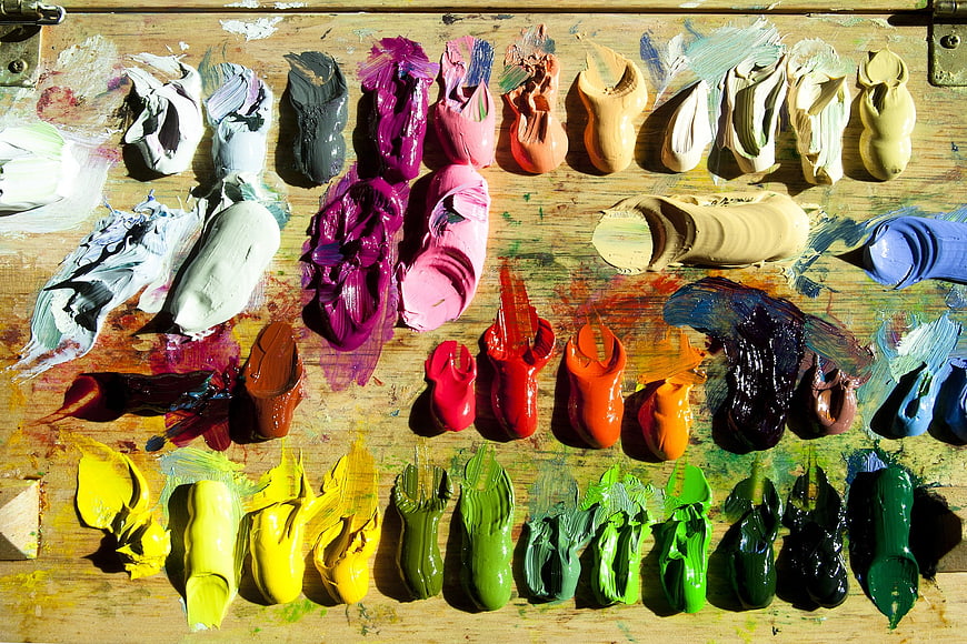 Vibrant oil paint blobs on a wooden artist palette