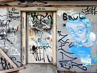 Urban graffiti mural with blue doll and tags on door