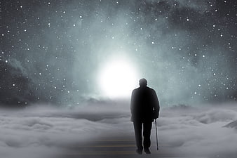 Silhouette of elderly man walking toward light in clouds