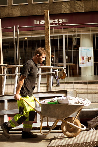 Construction Worker Pushing Wheelbarrow on Urban Site