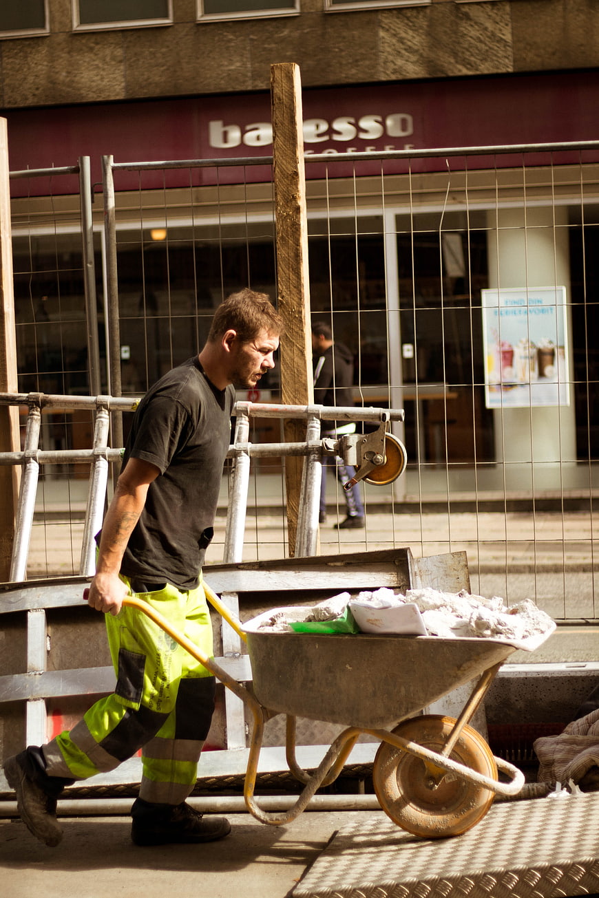 Construction Worker Pushing Wheelbarrow on Urban Site