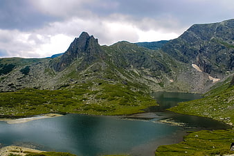 Alpine Lake Surrounded by Rugged Mountains and Green Hills