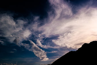 Dramatic Clouds Over Mountain Silhouette at Dusk