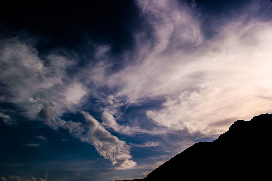 Dramatic Clouds Over Mountain Silhouette at Dusk