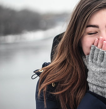 Woman Laughing in Winter Coat with Glove Over Mouth