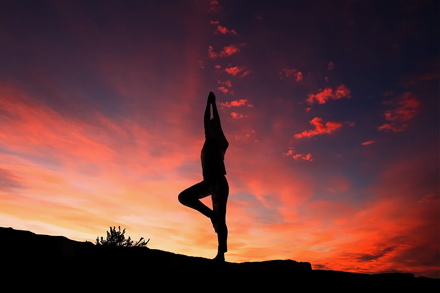 Silhouette of woman doing yoga tree pose at sunset