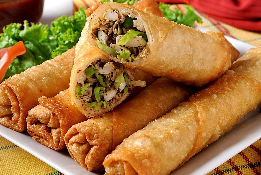 Crispy fried spring rolls with vegetable filling on white plate