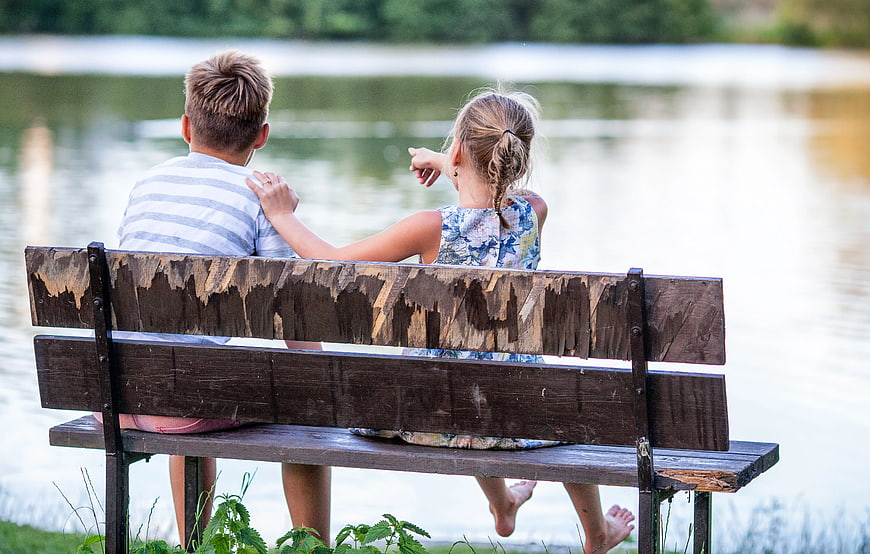 Children Sitting on Wooden Bench by Lake