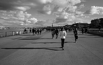 Black and white photo of people walking on Parisian riverbank
