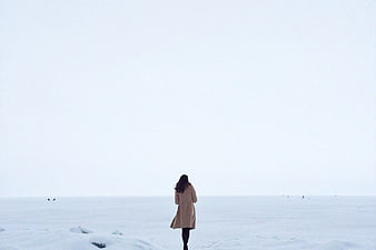Woman in Beige Coat Walking Alone in Snowy Landscape