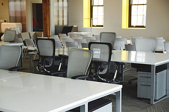 Modern empty office workspace with white desks and chairs