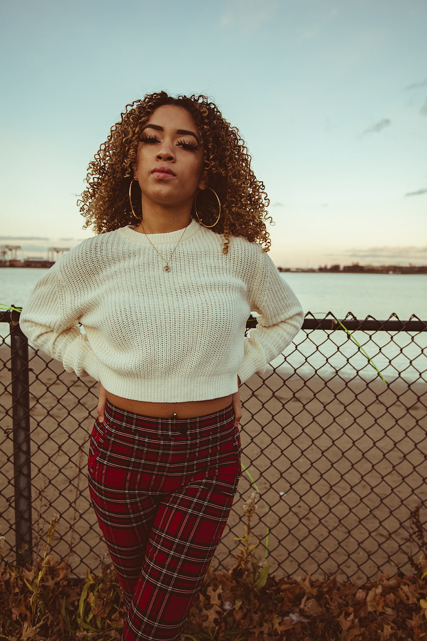 Stylish Woman in Plaid Pants and White Sweater by Water