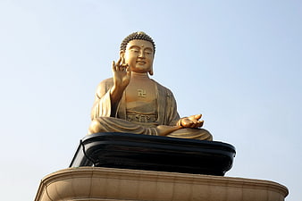 Golden Buddha Statue in Meditation Pose Against Clear Blue Sky