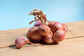 Fresh Red Onions on Wooden Table with Blue Background