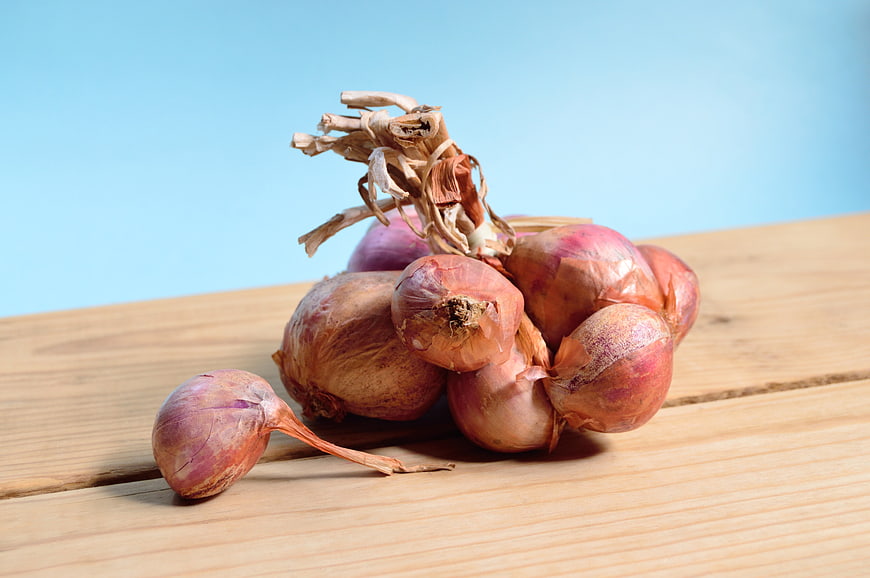 Fresh Red Onions on Wooden Table with Blue Background
