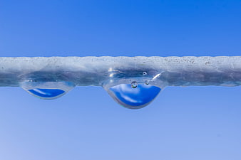 Close-up of melting ice rope with water droplets against blue sky
