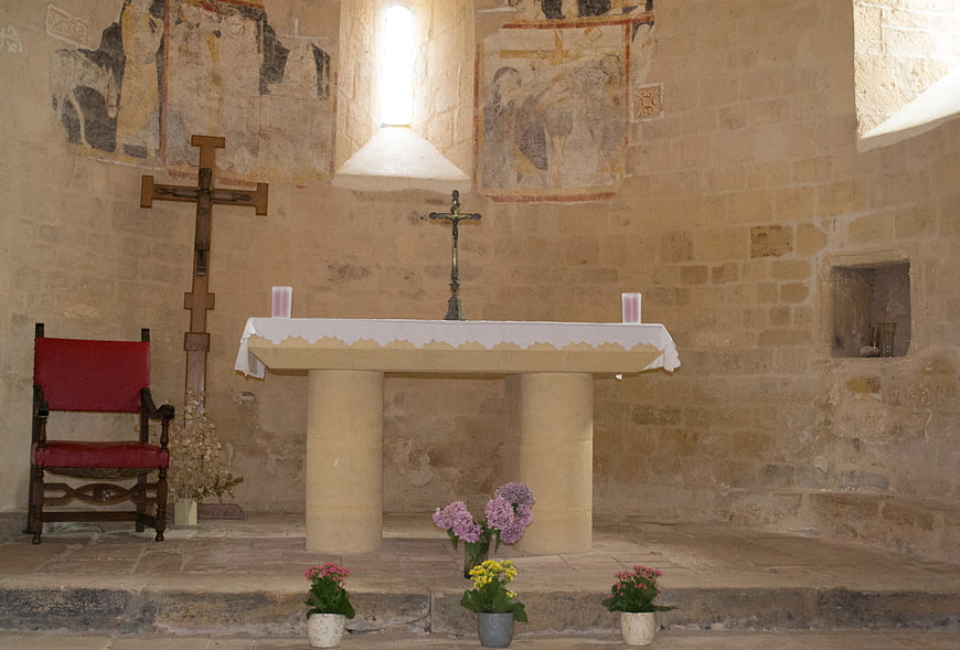 Rustic stone church altar with ancient frescoes and flowers