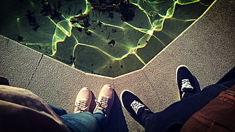 Couple's feet by pool edge with caustic light reflections