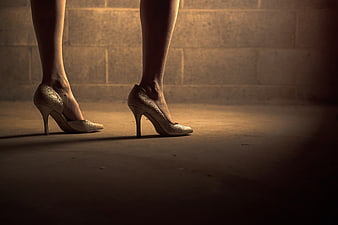 Woman's legs in gold glitter high heels on concrete floor